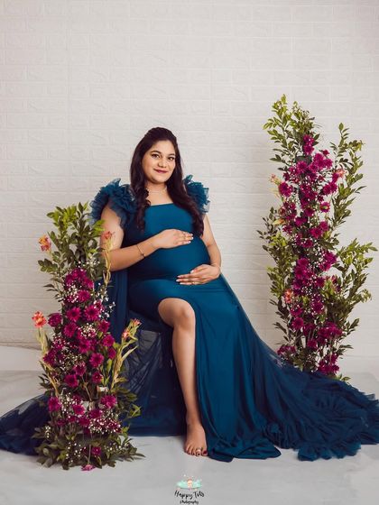 A seated pose that feels both regal and relaxed. The deep teal of the gown looks incredible against the vibrant floral props.
