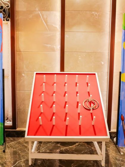 An art-themed twist on a classic carnival game. This ring toss setup is flanked by colorful banners matching the "Pranaya's Art Party" theme.