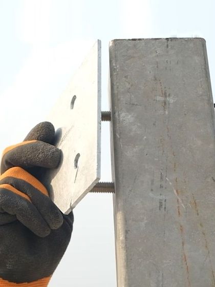 A close-up of a technician assembling the galvanized steel structure of a solar plant. Precise nut and bolt torquing is a critical detail that ensures the structural integrity, reliability, and safety of the entire system.