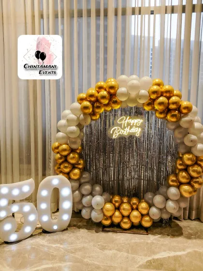 A full view of the elegant 50th birthday decoration. The combination of the balloon ring, neon sign, and light-up numbers against a clean backdrop makes for a timeless and celebratory photo stage.
