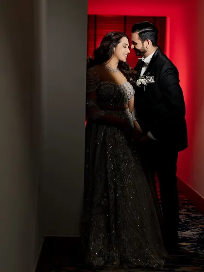 A romantic portrait of the couple in a hallway with dramatic red lighting, creating an intimate and passionate mood.