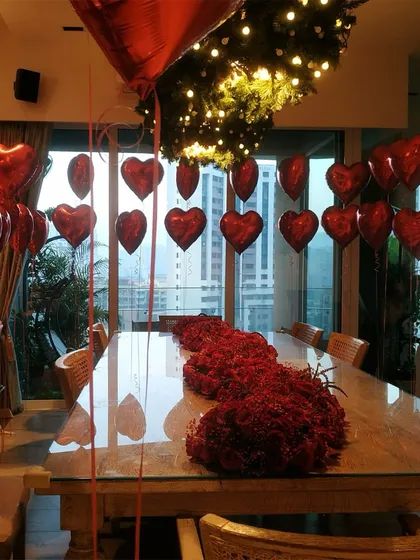 For an intimate Valentine's celebration, we filled this home with romance. The decor featured a cascade of red heart-shaped balloons and a stunning, dense runner of fresh red roses and baby's breath along the dining table, creating a luxurious and heartfelt ambiance.