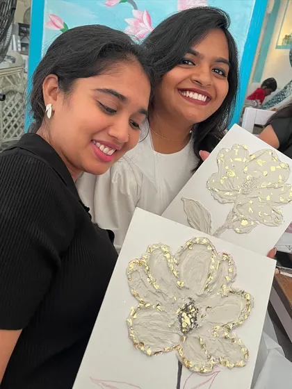 Two friends smiling with their beautiful, gold-accented texture art.