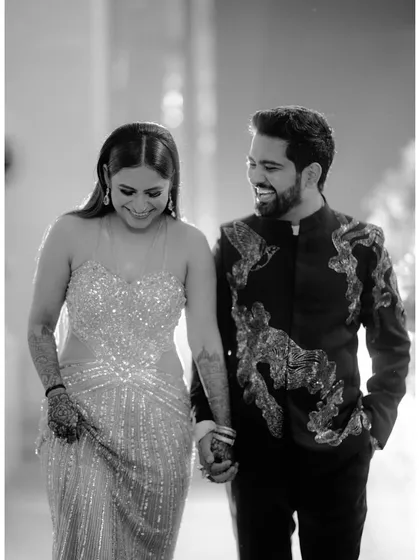The joy of walking together. This black and white candid shot captures the couple mid-laugh, holding hands as they move through their celebration, a perfect picture of shared happiness.