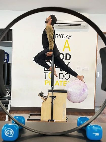 An artistic shot of a client on the Stability Chair, framed by the Pilates ring. This creative pose showcases balance, strength, and the fun we have in the studio.