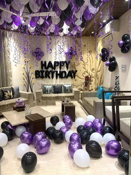 A full room view of the purple and black themed birthday decor. Loose balloons are scattered on the floor to complement the ceiling decorations, filling the entire space with a festive feel.