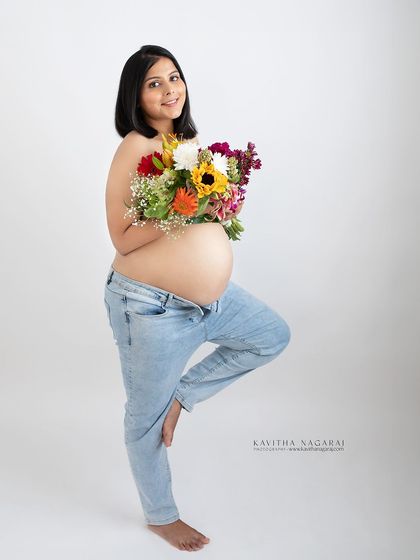 A simple and classic maternity pose. An expecting mother stands in tree pose, holding a bouquet of flowers, symbolizing balance, growth, and new life.