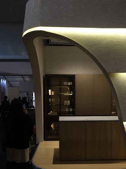 This detail shot focuses on the kitchen island and display cabinet within the Plüsch booth. The clean lines and high-end materials of the products are complemented by the soft, architectural shell I designed.