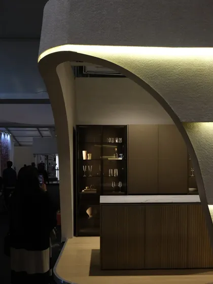 This detail shot focuses on the kitchen island and display cabinet within the Plüsch booth. The clean lines and high-end materials of the products are complemented by the soft, architectural shell I designed.