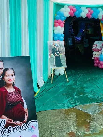 The entrance to a baby shower pandal, personalized with large photos of the expecting couple on easels.