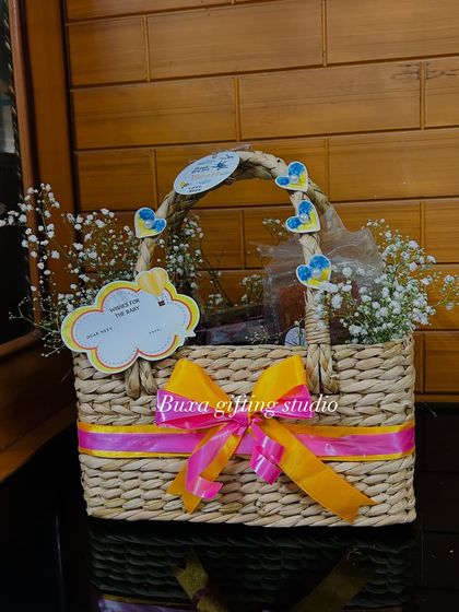 This handwoven kauna grass basket is filled with baby's breath and goodies, complete with a "Wishes for the baby" tag for guests to write on.