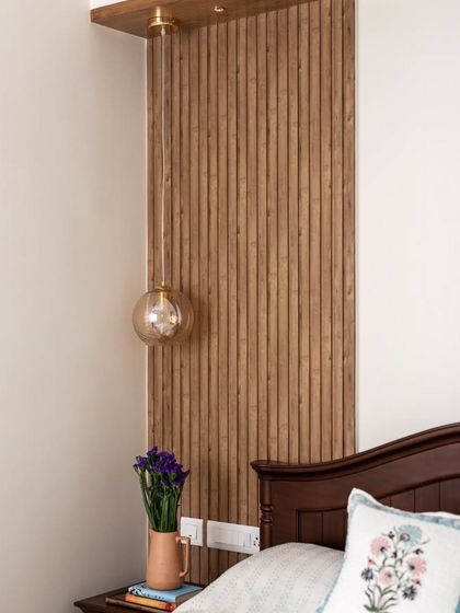 In this guest room, I used simple wooden rafters and a glass pendant light to complement the client's existing traditional bed, creating a warm and comfortable space with minimal intervention.