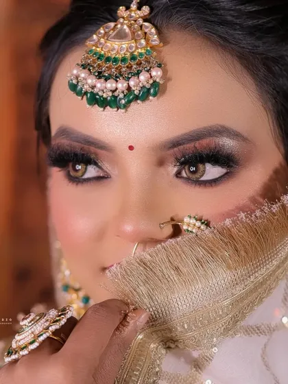 A detailed close-up of the bride's face, showing the flawless makeup and the intricate maang tikka.