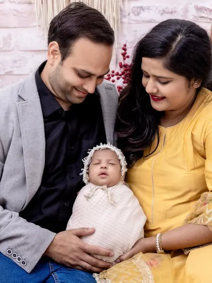 A heartwarming portrait of new parents admiring their sleeping baby. This photo captures the quiet, loving atmosphere of a family just beginning their journey together.