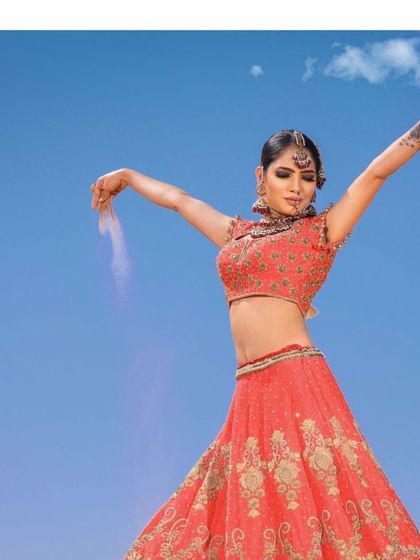 Captured against the endless sky, this coral-red bridal lehenga with all-over gold embroidery embodies the spirit of a summer bride. It is both radiant and timeless.