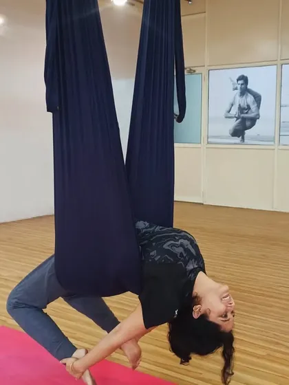 A student performs a graceful backbend while suspended in the aerial hammock. This pose beautifully opens the heart and shoulders, demonstrating the elegance of aerial practice.