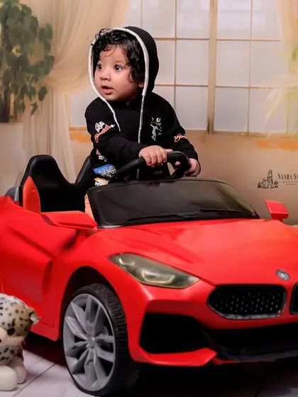 Another angle of the little driver in his red convertible. The soft, studio-lit background ensures that the baby and the car are the stars of the photo.