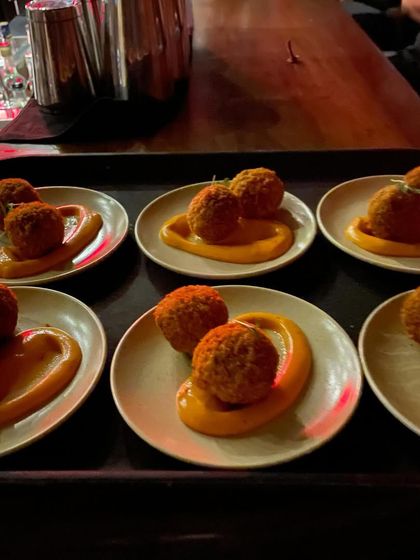 Golden, crispy croquetas served on a swirl of rich sauce. These savory bites were inspired by the running of the bulls in Pamplona, offering a taste of thrilling Spanish tradition.