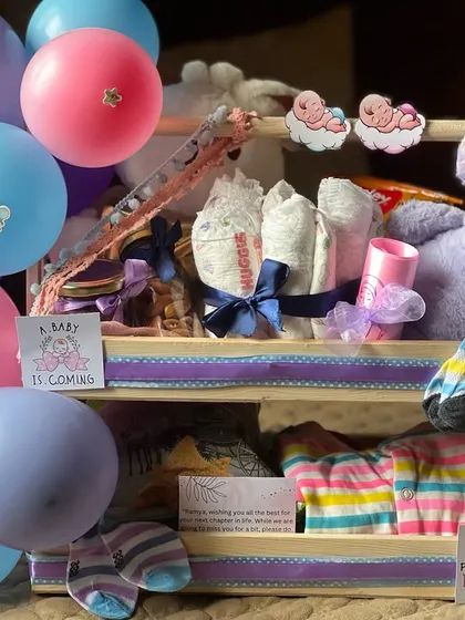 I love creating these multi-level displays. This two-tiered wooden stand is filled with newborn essentials like diapers, soft striped clothing, and a cuddly elephant toy, making it a beautiful and practical baby shower gift.