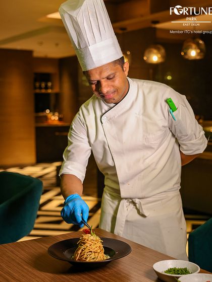 A chef at Zodiac puts the finishing touches on a spaghetti dish, demonstrating the care and precision we take in our food presentation.