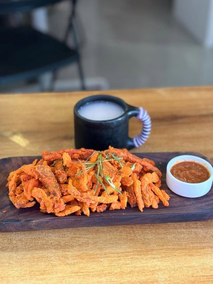 The perfect duo: our crispy pork bhujia served on a wooden platter alongside a mug of our traditional fermented rice drink. This combination is a true taste of Naga social gatherings.
