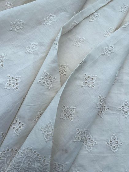 A classic white cutwork cotton with a delicate floral buti pattern. This fabric is timeless, breathable, and perfect for a sophisticated summer wardrobe.