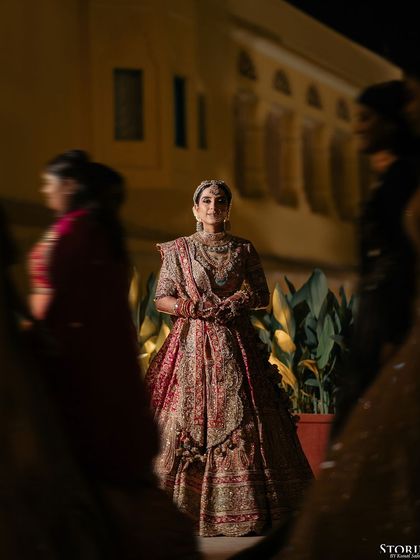 A candid shot of the bride, Aashi, during the ceremony, framed through the crowd, creating a sense of depth and intimacy.