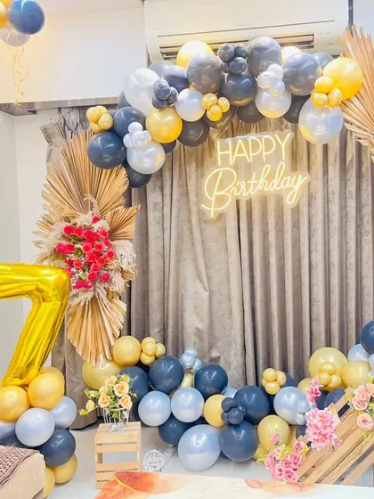 A rustic-chic 17th birthday decoration. The circular balloon arch is accented with dried palm leaves, and large foil balloons indicate the age.