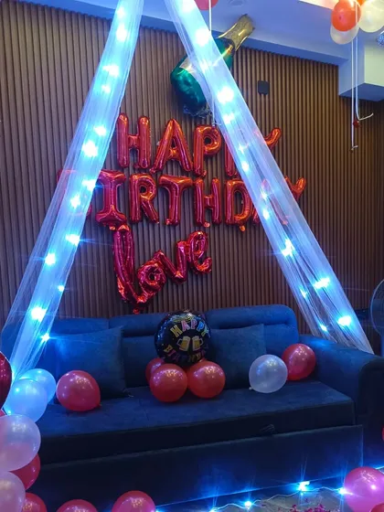 A cozy and romantic setup on a sofa with a canopy and fairy lights. The "Happy Birthday Love" foil balloons make it a perfect surprise for your special someone.