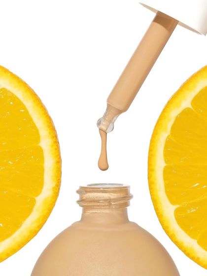 A minimalist and conceptual take on an ingredient shot. The serum bottle is framed by two perfect halves of an orange, with a single drop suspended in the air, creating a clean and powerful visual.