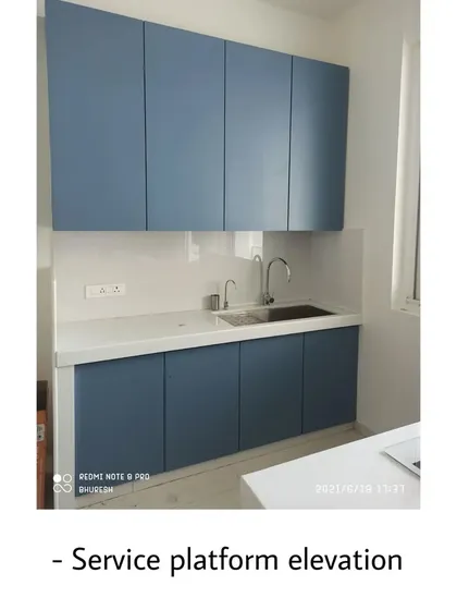 The service platform area of the Andheri kitchen, featuring a sink and additional storage. The clean lines and simple color palette make the space feel open and uncluttered.