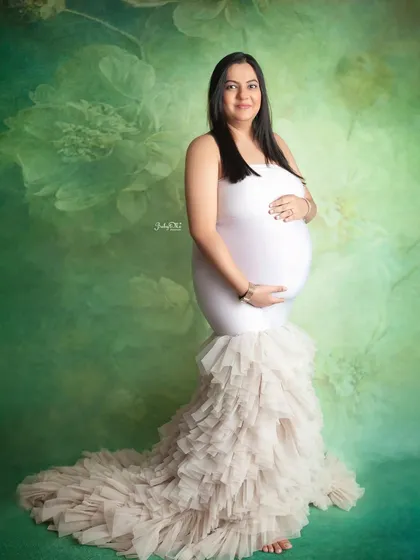 This beautiful mom-to-be chose a white mermaid gown with a ruffled train, which looks so lovely against this soft green floral backdrop. It’s such a graceful and feminine look.