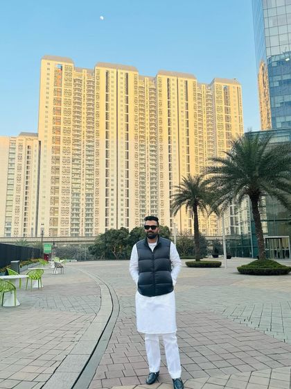 Standing in a plaza with a modern high-rise in the background. I live by the words of Sahir Ludhianvi, to face every worry of life and move forward.