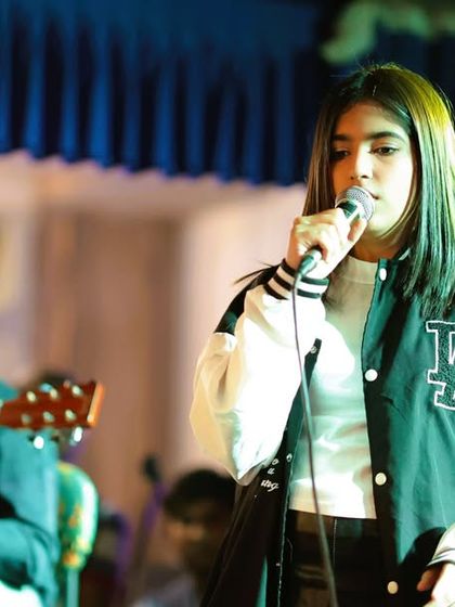 A vocalist and guitarist share the spotlight. Our program encourages different combinations of instruments and voices, helping students learn to arrange and perform songs together.