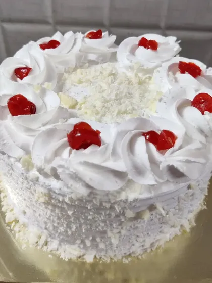 My take on the timeless White Forest cake. It's covered in white chocolate shavings and whipped cream frosting, then topped with bright red cherries for that iconic look and taste.
