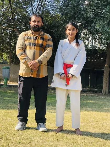 A female student proudly stands with the sensei after her red belt promotion. She is a powerful martial artist and an inspiration.