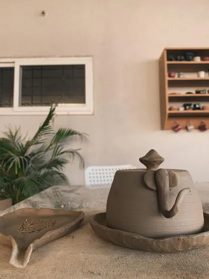 An unglazed, elephant-handled jar next to a triangular ashtray. Functional art with a touch of whimsy.