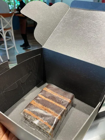 A single, perfectly layered cake slice, packaged and ready to go.