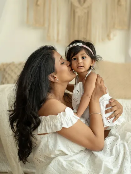 A mother's gentle kiss for her daughter. A timeless and loving portrait.
