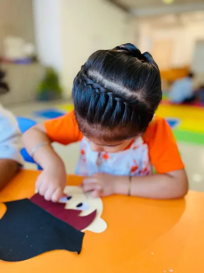 A beautiful shot of a girl's intricate hairstyle as she focuses on her craft project.