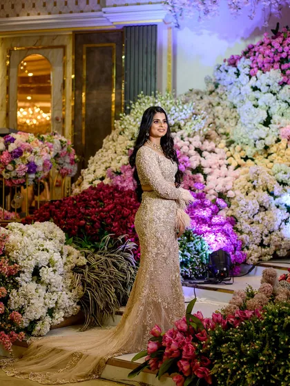 A beautiful solo portrait of the bride-to-be, her elegant gown flowing against a stunning wall of multi-colored flowers.
