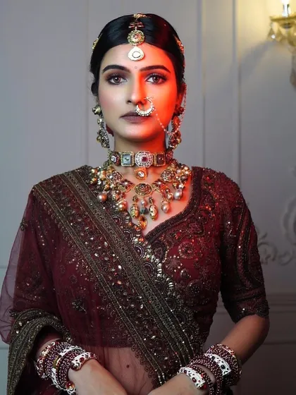 A dramatic portrait of the maroon phera look. The makeup is sculpted and defined to stand out, with a focus on bronzed, smokey eyes.
