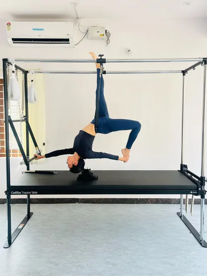 A graceful backbend pose suspended from the Cadillac, highlighting spinal mobility and control.