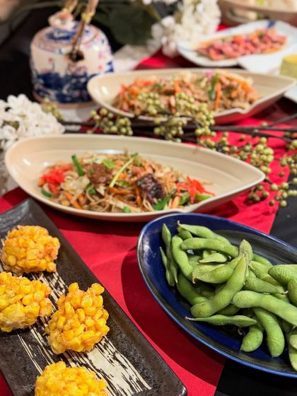 A selection of our cold appetizers, including edamame, corn fritters, and a Japanese noodle salad, as part of a larger catering setup. These dishes are perfect for warm weather or as a refreshing start to a meal.