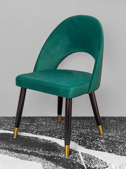 The same comfortable and stylish dining chair, shown here in a rich emerald green velvet. This pop of color can elevate any dining room or serve as a beautiful accent chair in a living space.