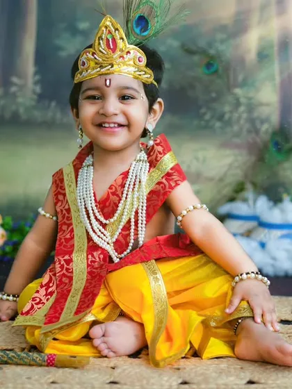A joyful little Krishna celebrating Janmashtami. His bright smile and festive attire make this a truly special and happy portrait.