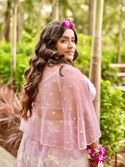 An over-the-shoulder shot that shows the back of her cape and her beautiful, wavy hair adorned with flowers. The makeup from this angle looks soft and natural.