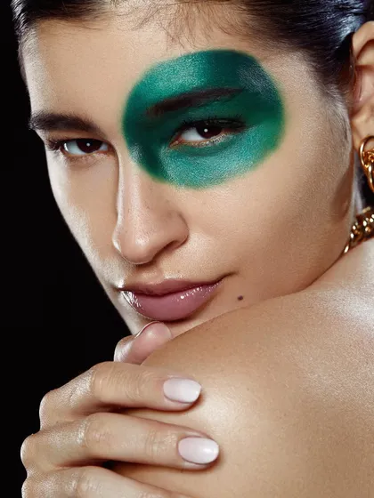 An abstract, artistic look with a bold circle of green pigment over one eye, showcasing creative expression.