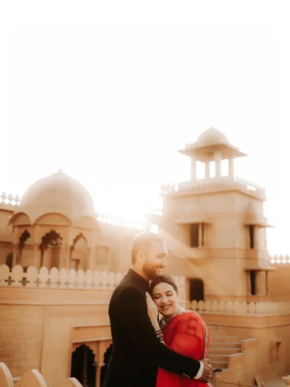 An intimate embrace against a grand, sunlit palace. This photo captures a tender moment, combining the epic scale of the location with the personal connection of the couple.