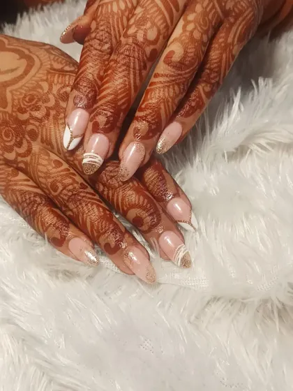An elegant nail extension set designed for a bride. The design features a modern French look with white and gold glitter accents that beautifully complement the traditional henna.